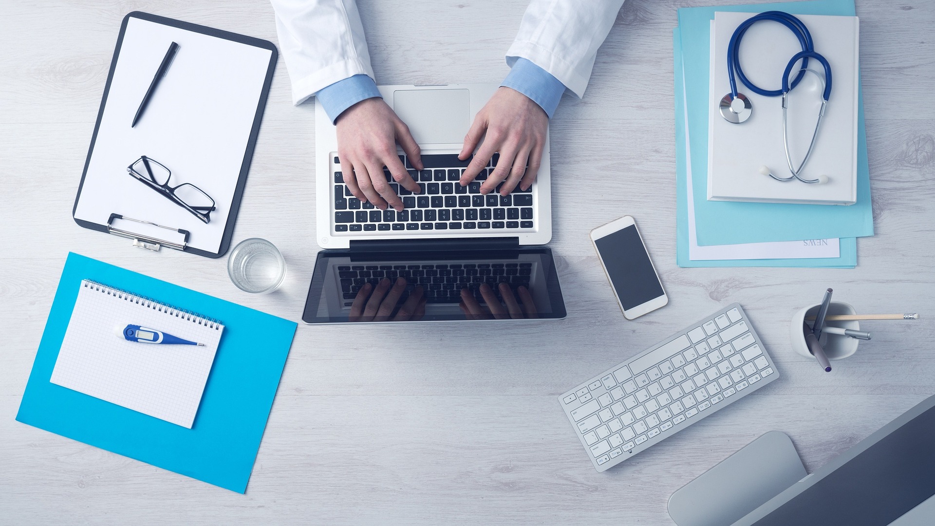 Doctor working on a laptop with medical tools on a desk